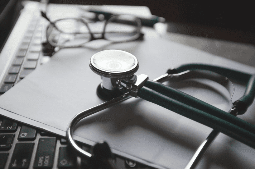 A stethoscope placed on a sheet of paper, lying on a computer keyboard